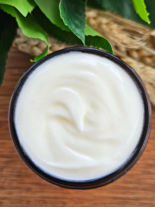 Jar of white cream with green leaves on a wooden surface