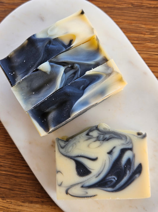 Three bars of soap with black and white swirl patterns on a marble surface.