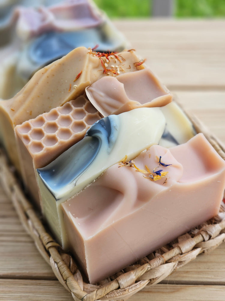 Natural soap bars with honeycomb pattern on a wicker tray with green grass in the background