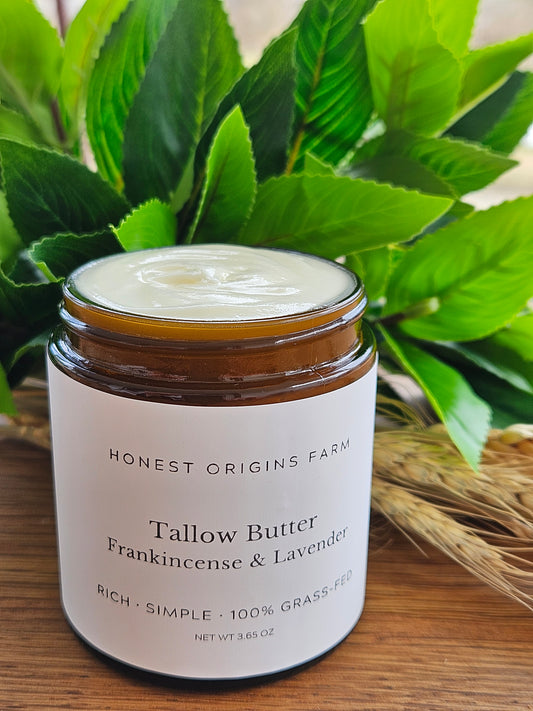 Jar of tallow butter with a label on a wooden surface with green leaves in the background