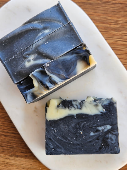 Four bars of black and white soap on a marble slab