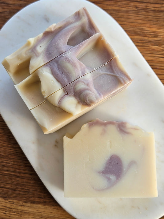 Three bars of soap with a marbled design on a marble slab.