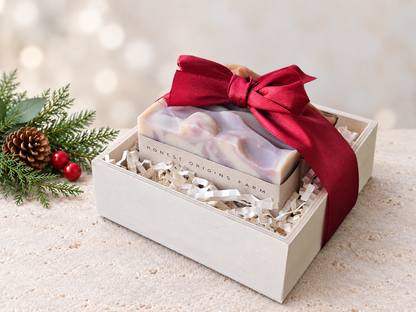 Three soaps in a wooden crate/box with a red satin bow and Christmas accents.