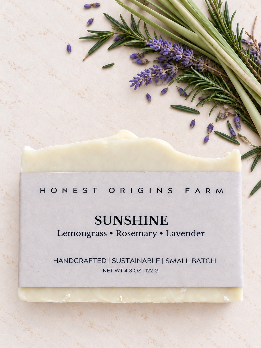 A handcrafted bar of soap from Honest Origins Farm, labeled 'Sunshine' with notes of lemongrass, rosemary, and lavender, styled on a light textured background with fresh rosemary and lavender sprigs.