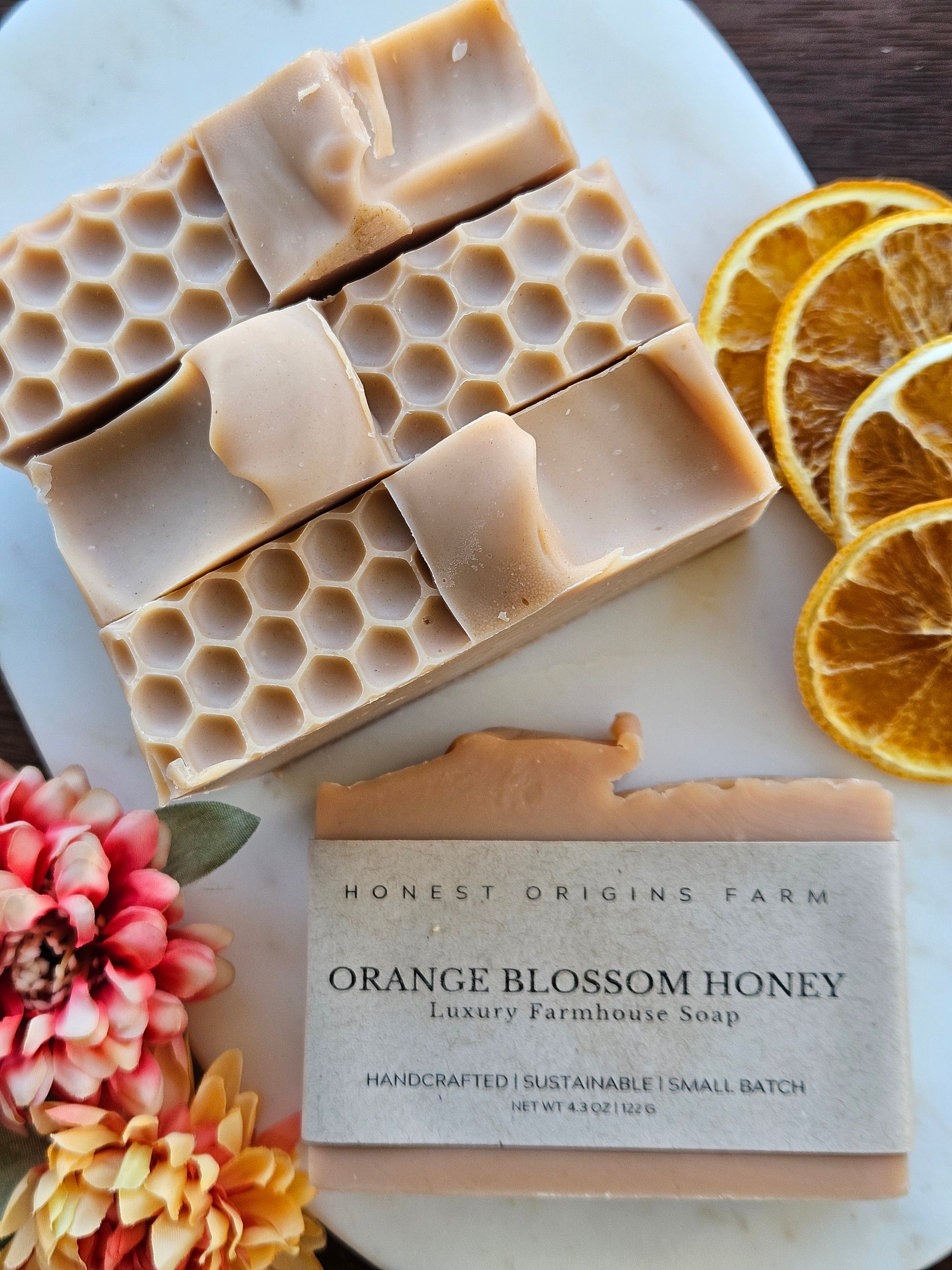 Handmade soap bars with honeycomb design and a bar of Honest Origins Farm Orange Blossom Honey soap on a decorative plate.