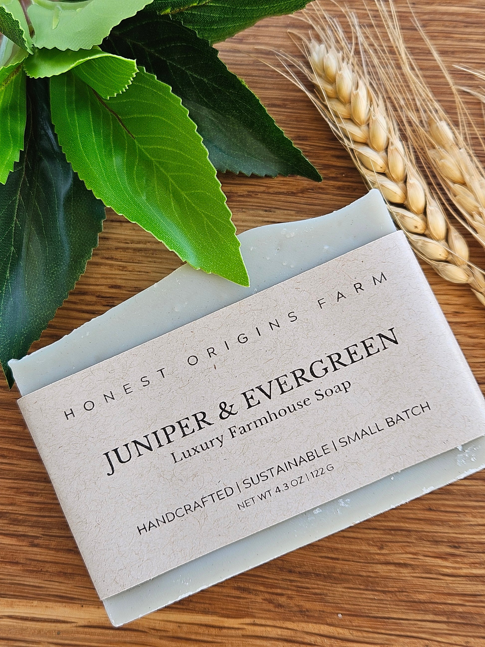 Bar of soap with a label on a wooden surface with leaves and wheat.