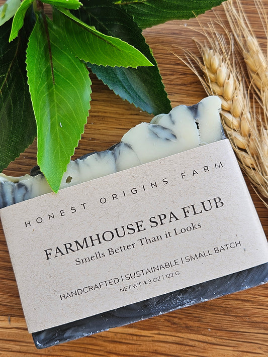 Bar of soap with a label on a wooden surface with leaves and wheat.