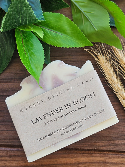 Bar of soap with a label on a wooden surface surrounded by green leaves