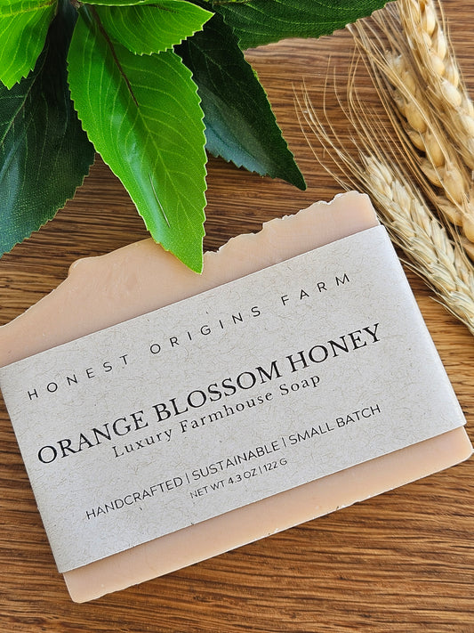 Bar of soap with a label on a wooden surface with leaves and wheat ears.