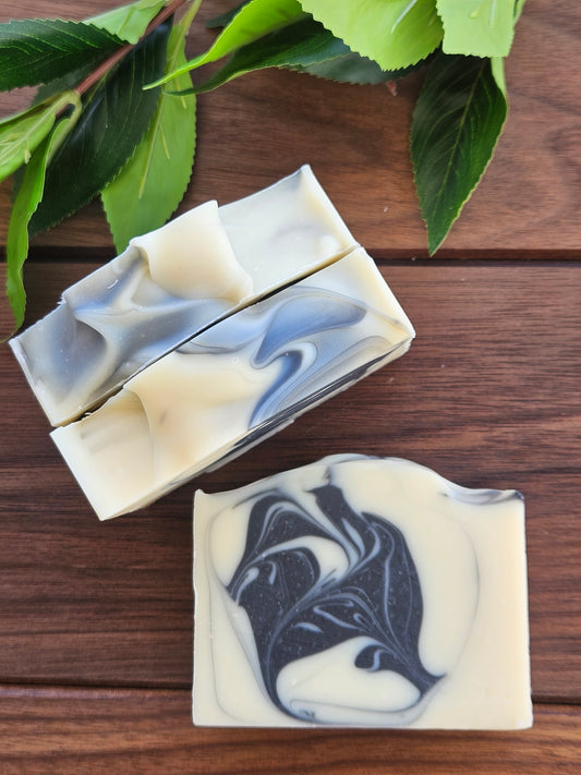 Marbled soap bars on a wooden surface with green leaves.