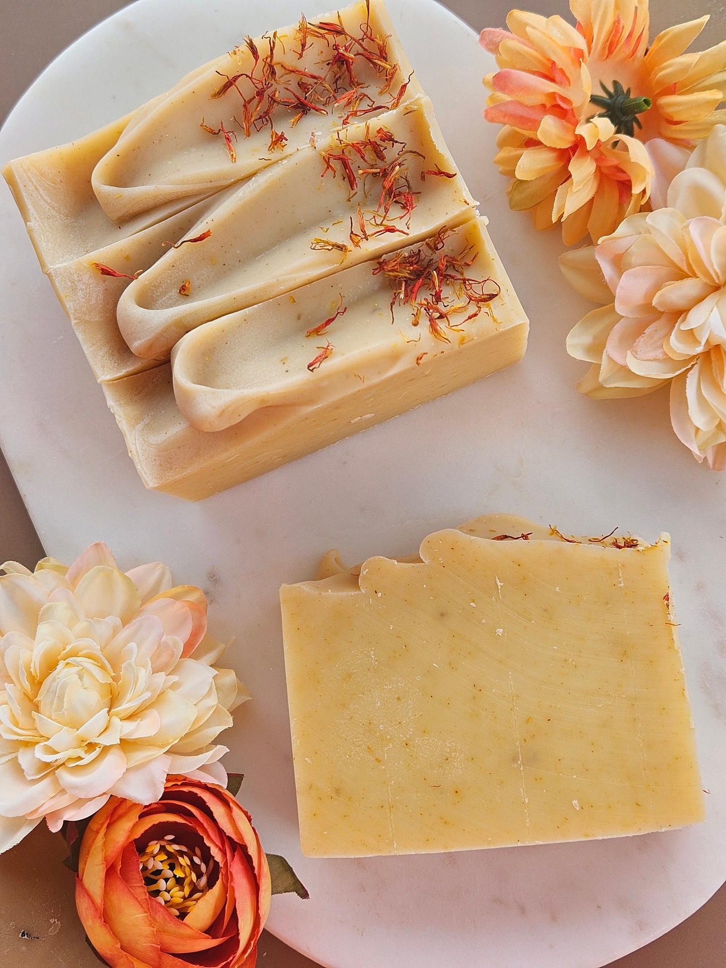 Two bars of soap with floral elements on a marble surface